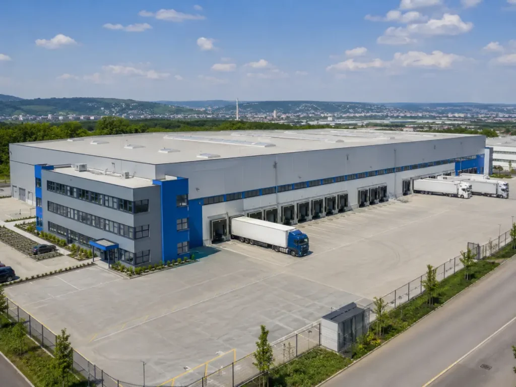 Freistehende moderne Lager- und Logistikhalle mit Verladerampen, Bürotrakt und Lkw-Hof in einem Gewerbegebiet der Region Stuttgart, erhöhte Perspektive, Tageslicht, seriös.